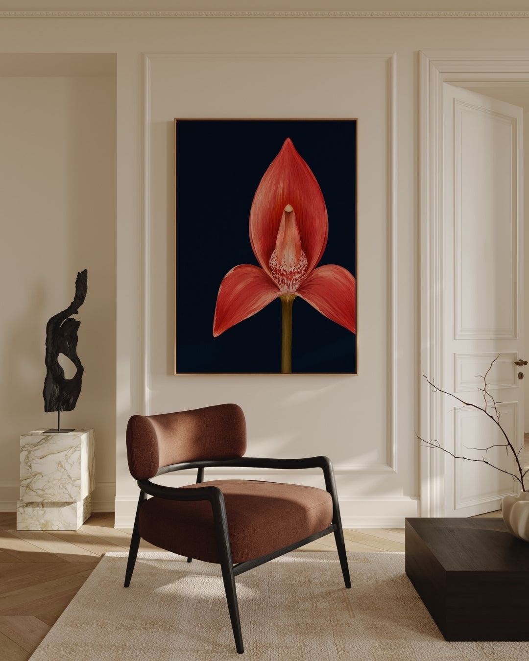 A framed wall art print featuring a large red orchid flower on a dark navy background, displayed in a styled interior room with a brown upholstered chair, cream walls, and decorative objects.