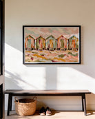 A framed painting of colorful beach huts hangs on a white wall above a wooden bench with a woven basket and shoes underneath.
