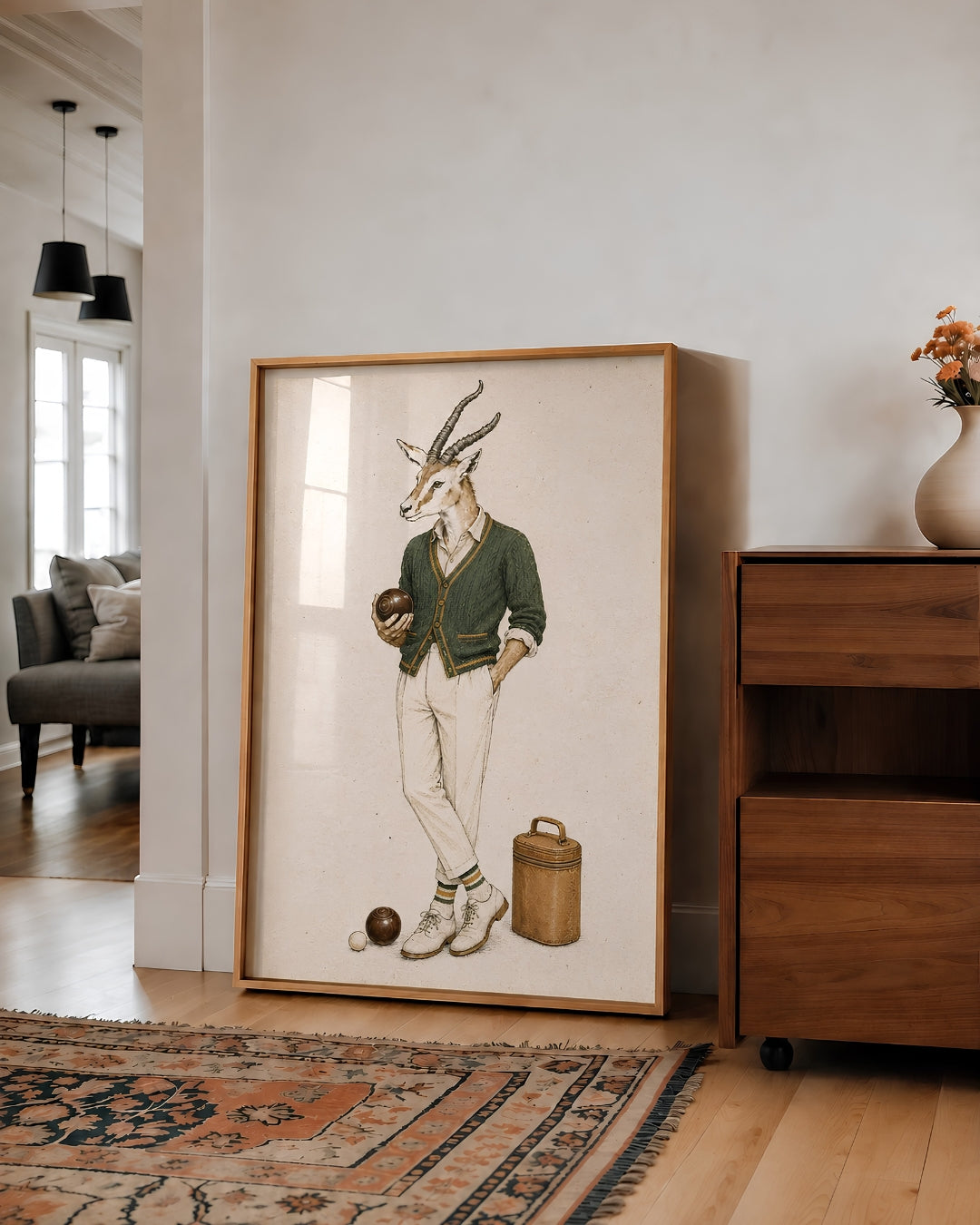 A large framed art print featuring a whimsical illustration of a gazelle dressed in vintage bowling attire, leaning against a white wall in a modern living room setting.