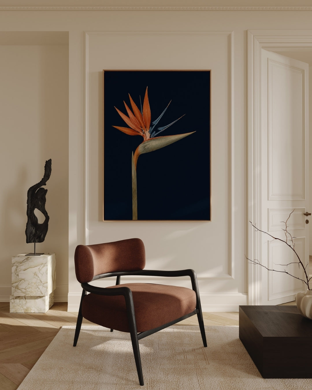 A framed vertical wall art print featuring a single bird of paradise flower on a very dark navy background, displayed in a styled interior room above a brown armchair.